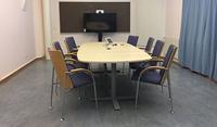 Mötesrum med bord och stolar, videokonferensutrustning