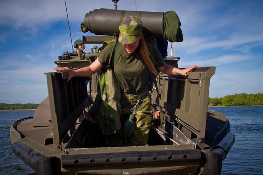 Foto på en soldat som står på en båt tillhörande Försvarsmakten