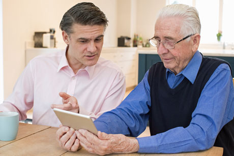 Two men sitting, focussing on an IPad