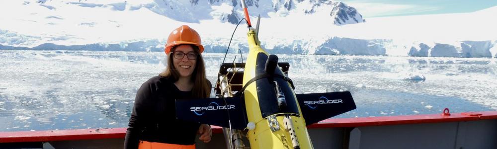 Researcher Louise Biddle with ocean glider Semla in front of an iceberg.