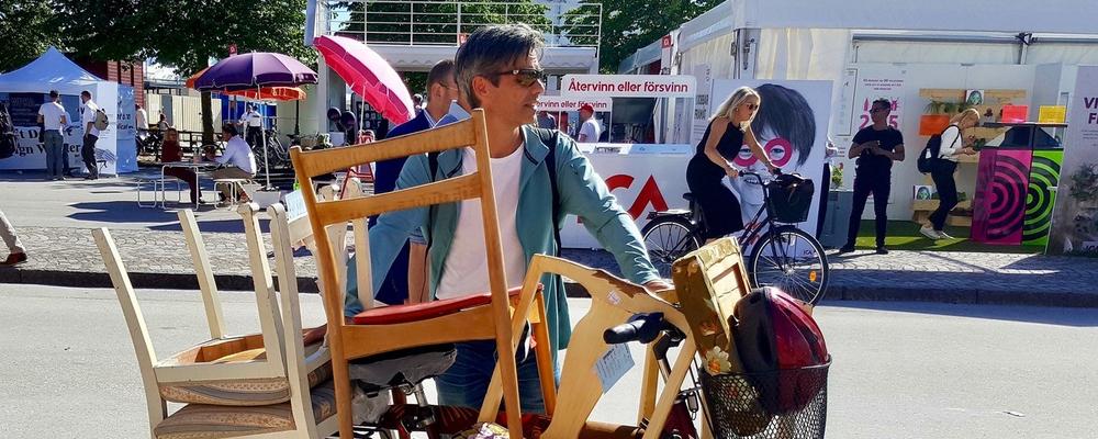 Staffan Appelgren rullar en cykel lastad med stolar genom ett somrigt Visby under Almedalsveckan
