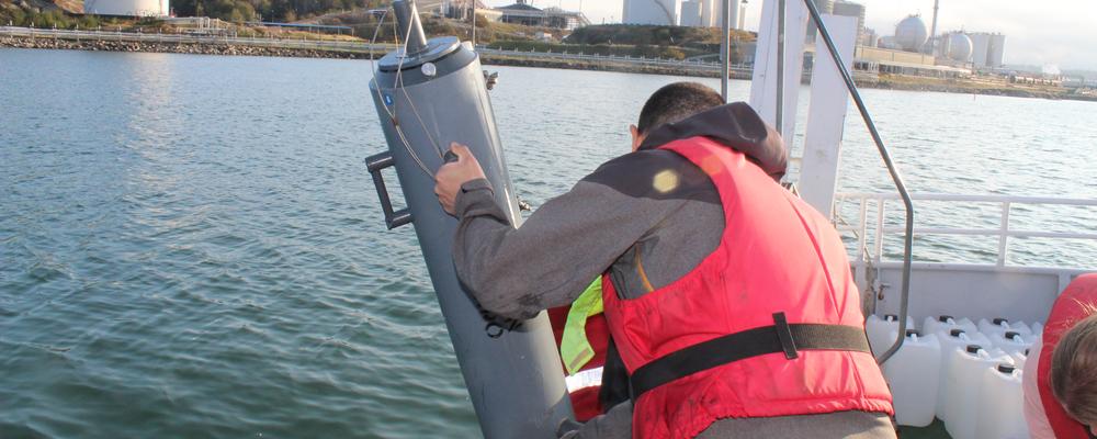 Sampling tube being collected from the sea by a man in a boat.