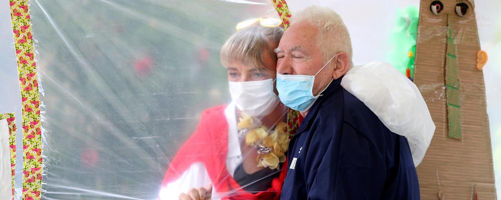 A 86-year-old resident at a Belgian nursing home hugs the director of the residence, through a wall made with plastic sheets to protect against COVID-19 infection.