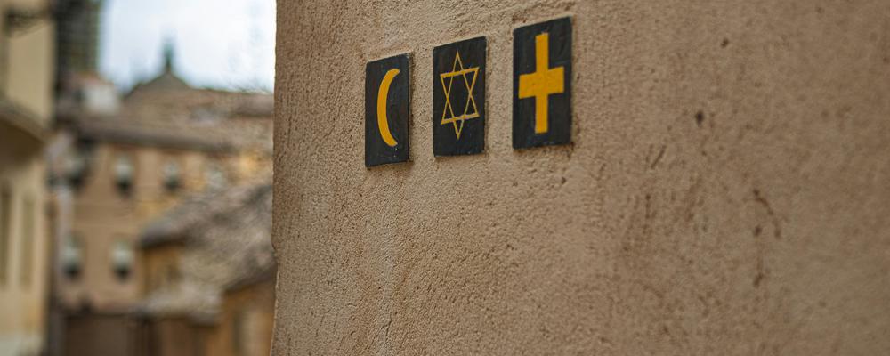Foto av en husfasad med tre religiösa symboler
