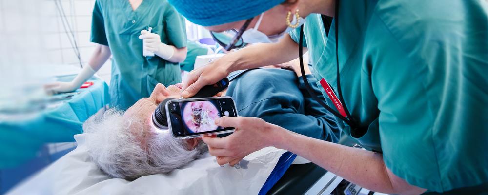 Kirurgen Hannah Ceder undersöker äldre patient som opereras för basalcellscancer