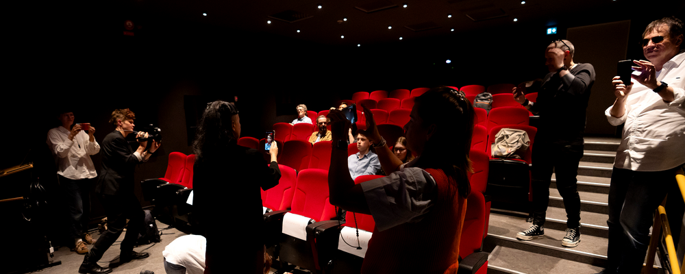 A group of people in a cinema filming and documenting the situation