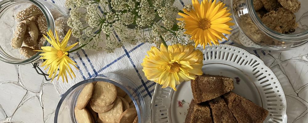 Olika kakor på ett bord med blommor i vas