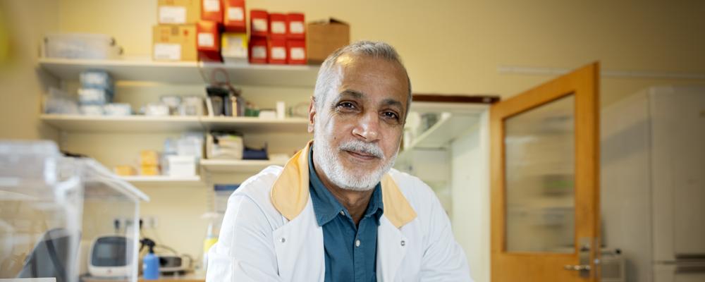 Hadi in lab wearing a lab coat, looking friendly