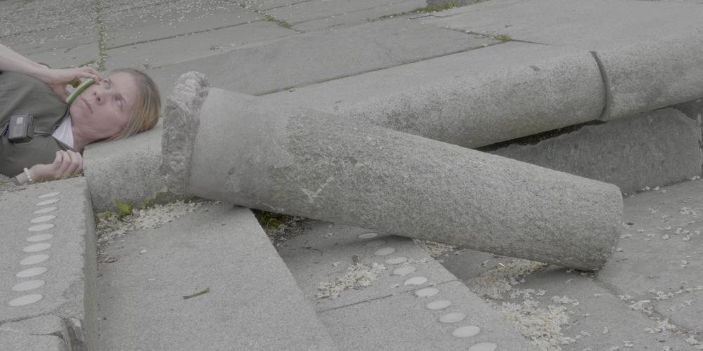 A person lying on the ground next to a broken column
