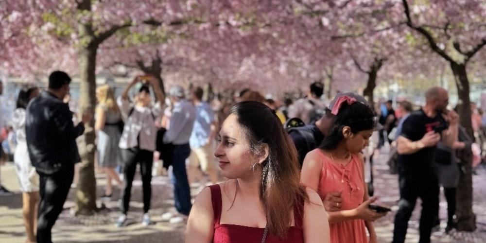 Utbytesstudenten Nayana framför japanskt körsbärsträd i full blom.