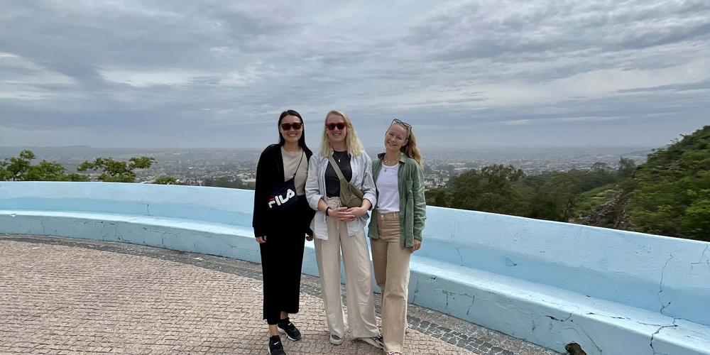 Signe Schjott med två vänner framför vacker utsikt i Angola.