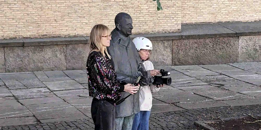 Två personer står med kameror i händerna vid en staty